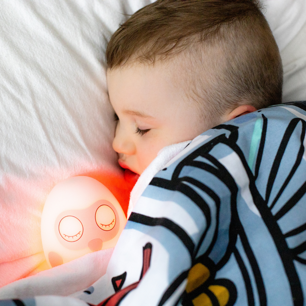 Ooly sleep clock with red glow in bed with boy